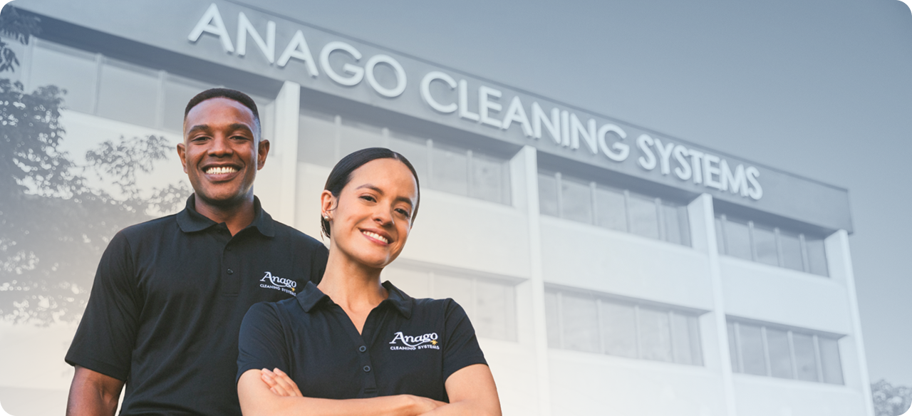 Two Anago Cleaning Systems employees standing outside a commercial building with the Anago Cleaning Systems sign